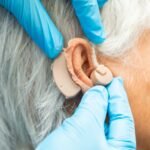 Paciente mayor sordo que usa un audífono para tratar el problema de pérdida auditiva.